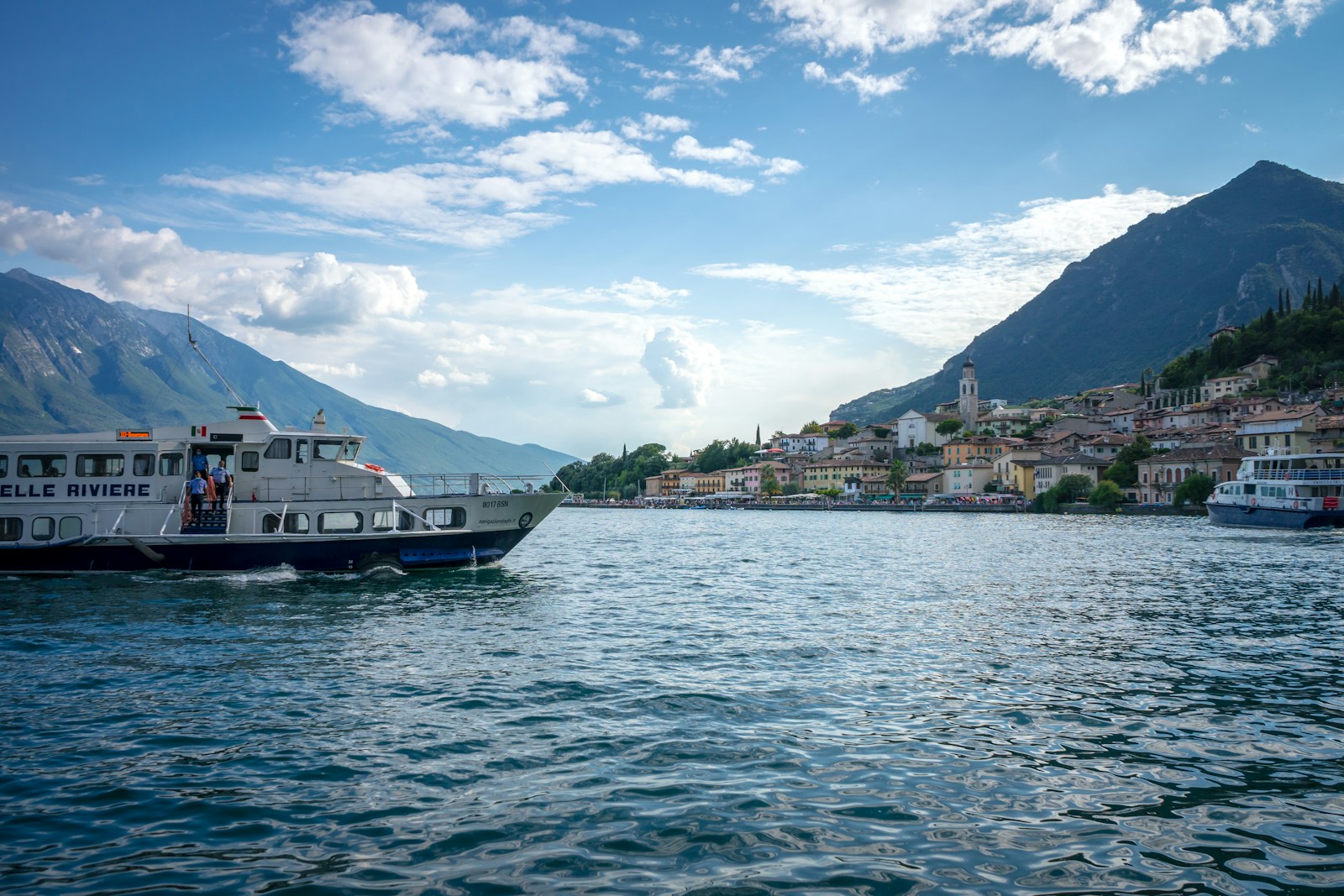 white and black boat on water near green mountain under blue sky during daytime